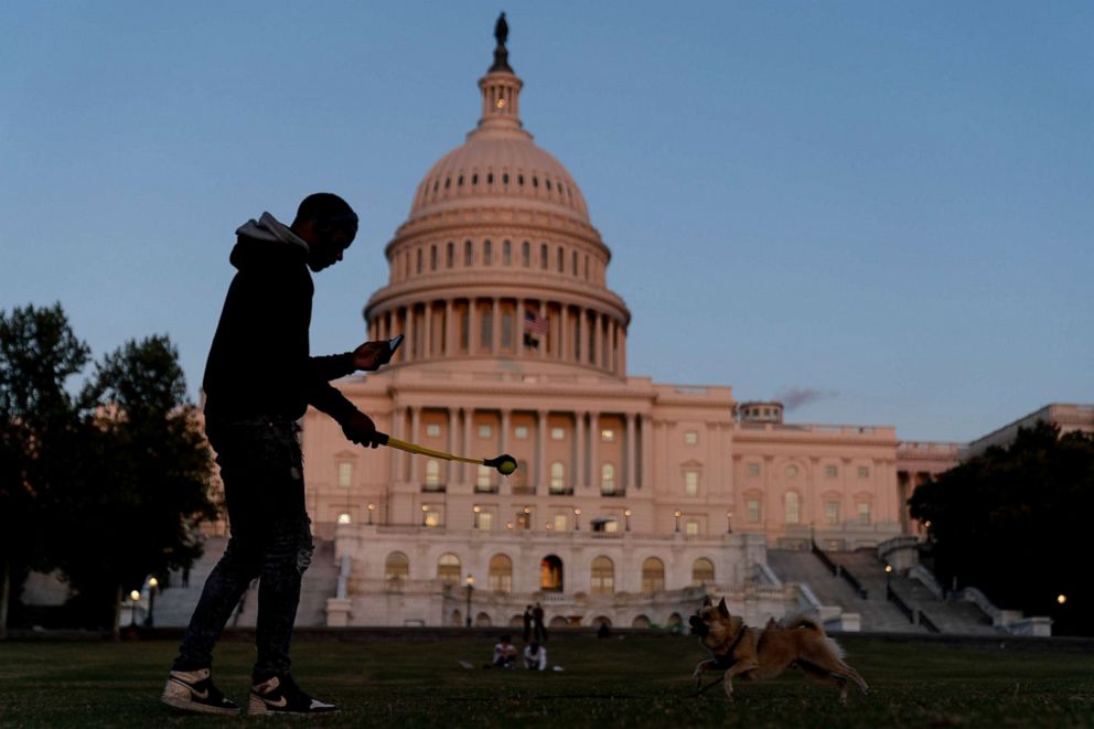PHOTO: The U.S Capitol is visible at sunset as a man plays fetch with a dog in Washington, Sept. 30, 2021.