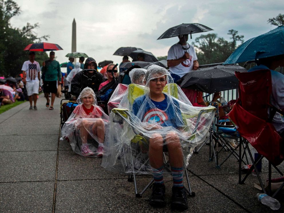 PHOTO: People cover from the rain as they gather on the National Mall ahead of the Salute to America Fourth of July event with President Donald Trump at the Lincoln Memorial in Washington, July 4, 2019.