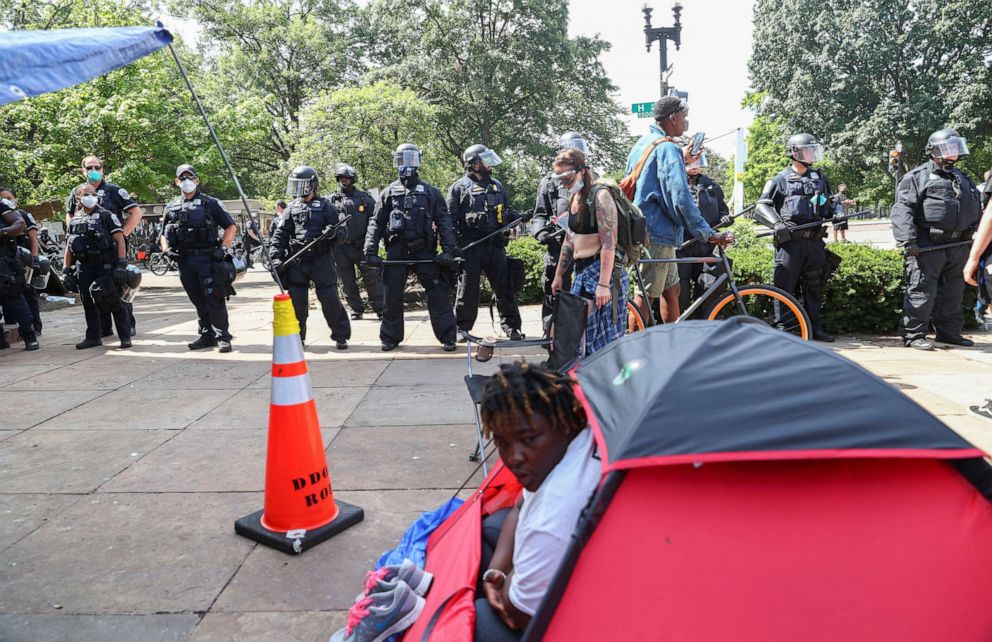 PHOTO: A person looks out of their tent as Washington, D.C. Metropolitan Police officers approach to clear the Black Lives Matter Plaza area in front of St. John's Episcopal Church during protests near the White House in Washington, June 23, 2020.