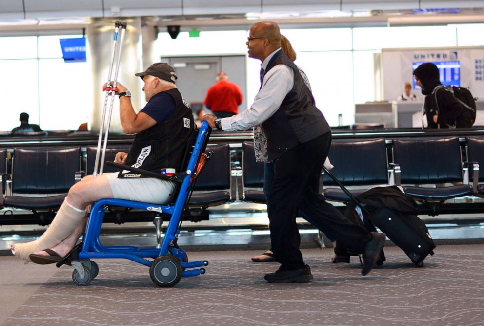 PHOTO: A customer care agent employed by G2 Secure helps a disabled passenger get to his boarding gate at Denver International Airport in Denver, Sept. 1, 2019.