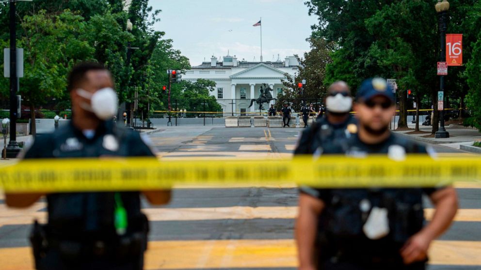 PHOTO: TOPSHOT - Police officers stand behind a police line as they block a road in 'Black Lives Matter' plaza near the White House in Washington, June 24, 2020.