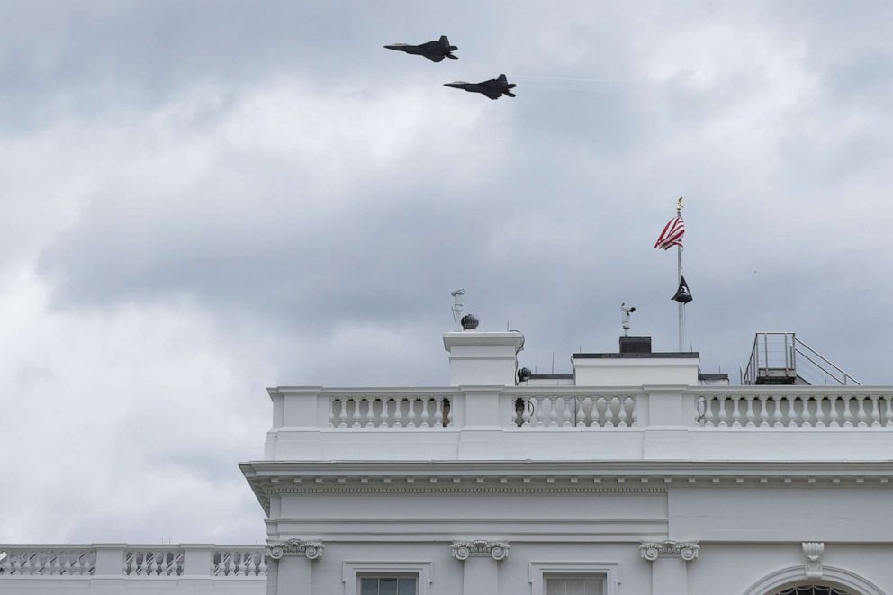 PHOTO: Two military aircraft fly over the White House on April 16, 2021 in Washington, DC. The US Air Force F-22 fighter aircraft flew over Washington as part of the World War I memorial dedication ceremony.