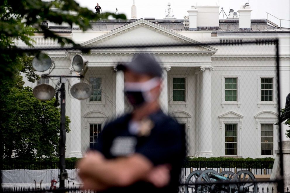 PHOTO: The White House is visible behind a large security fence as a uniformed Secret Service agent stands on the street in front of Lafayette Park in the morning hours in Washington, June 2, 2020, as protests continue over the death of George Floyd.