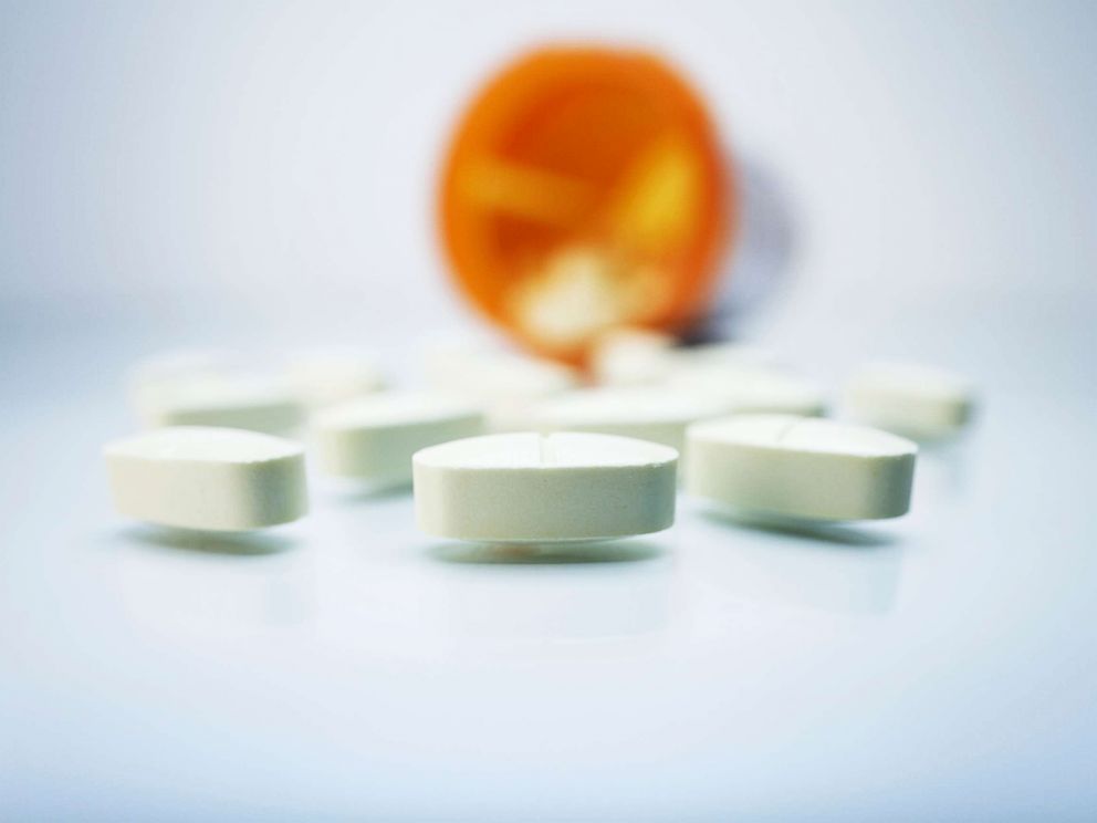 PHOTO: White pills and a plastic prescription pill container.