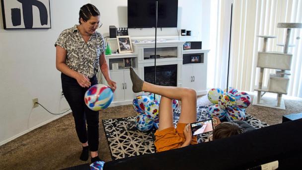 Havalah Hopkins, a single mother who lives in government-subsidized housing with her teenage son, talks with her son as she blows up balloon displays for his birthday, Thursday, July 10, 2025, at their apartment in Woodinville, Wash. (AP Photo/Lindsey Wasson)
