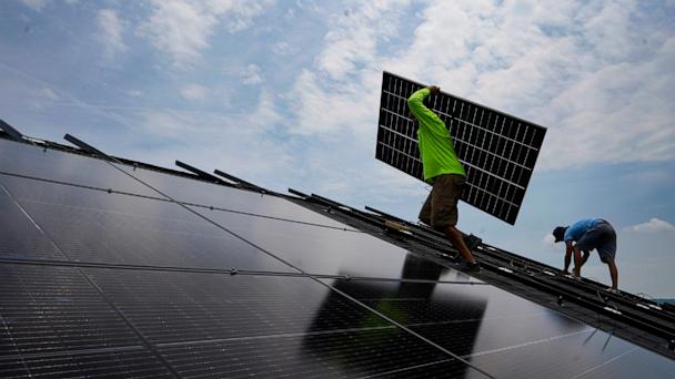 FILE - Nicholas Hartnett, owner of Pure Power Solar, carries a panel as he and Brian Hoeppner, right, install a solar array on the roof of a home in Frankfort, Ky., July 17, 2023. (AP Photo/Michael Conroy, File)