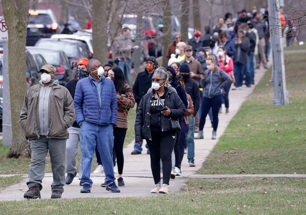 PHOTO: Voters wait in a line to vote in the presidential primary election while wearing masks and practicing social distancing to help slow the spread of coronavirus disease (COVID-19) at Riverside High School in Milwaukee, April 7, 2020. 