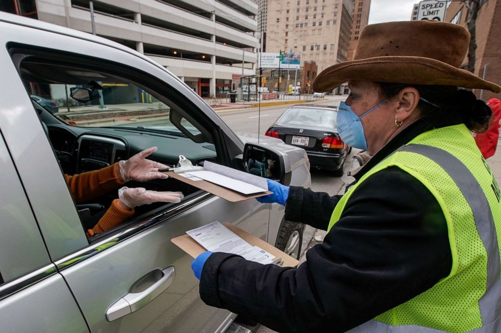 PHOTO: Jill Mickelson helps a drive up voter outside the Frank P. Zeidler Municipal Building Monday March 30, 2020, in Milwaukee. The city is now allowing drive up early voting for the state's April 7 election.