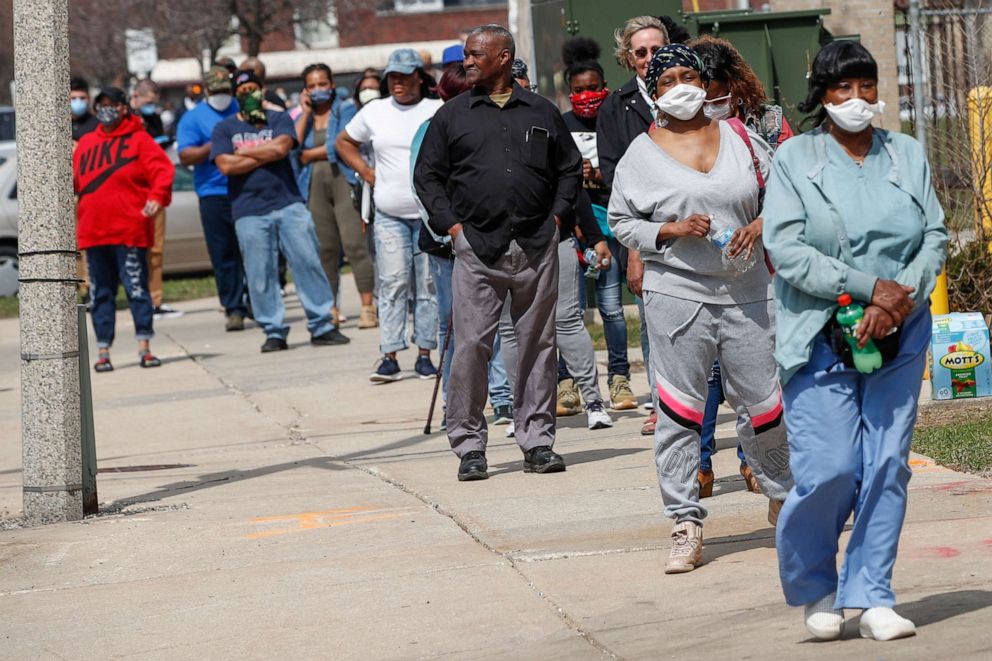 PHOTO: People wait in long line to vote in a presidential primary election outside the Riverside High School in Milwaukee, on April 7, 2020.