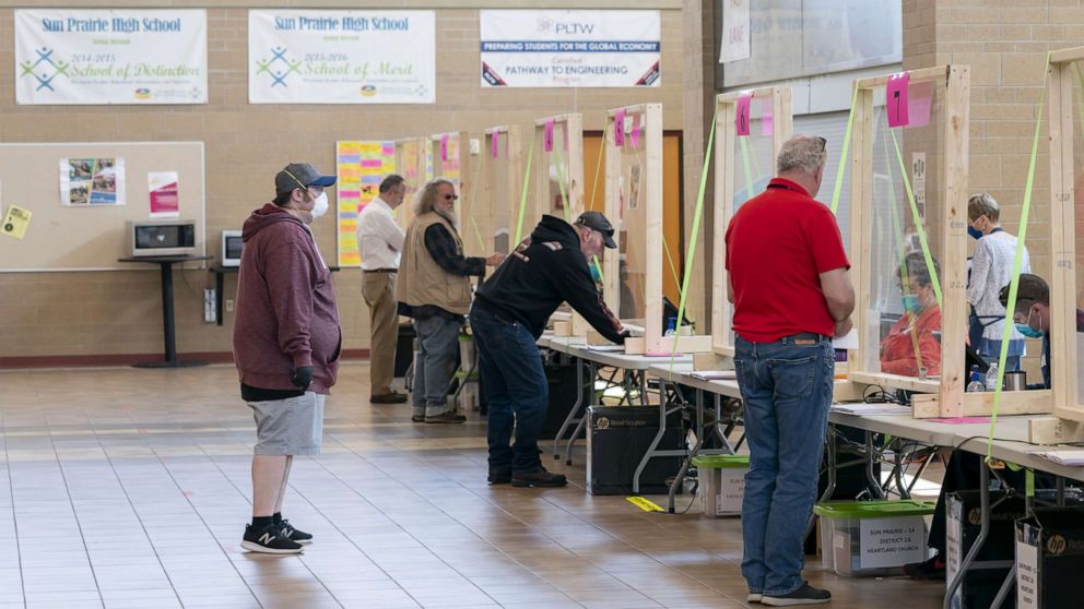 PHOTO: People check in to vote at a polling location, April 7, 2020, in Sun Prairie, Wisc.