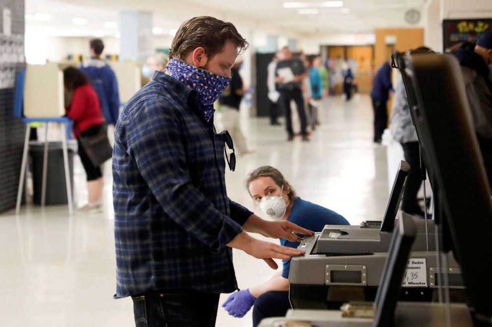 PHOTO: Voter Matt Phillips feeds his completed ballot into a counting machine inside a polling station at Hamilton High School during the presidential primary election, held amid the coronavirus disease (COVID-19) outbreak, in Milwaukee, Wisconsin.