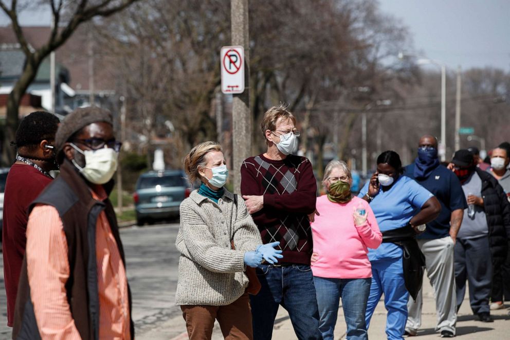 PHOTO: Residents wait in long line to vote in a presidential primary election outside the Riverside High School in Milwaukee, April 7, 2020.