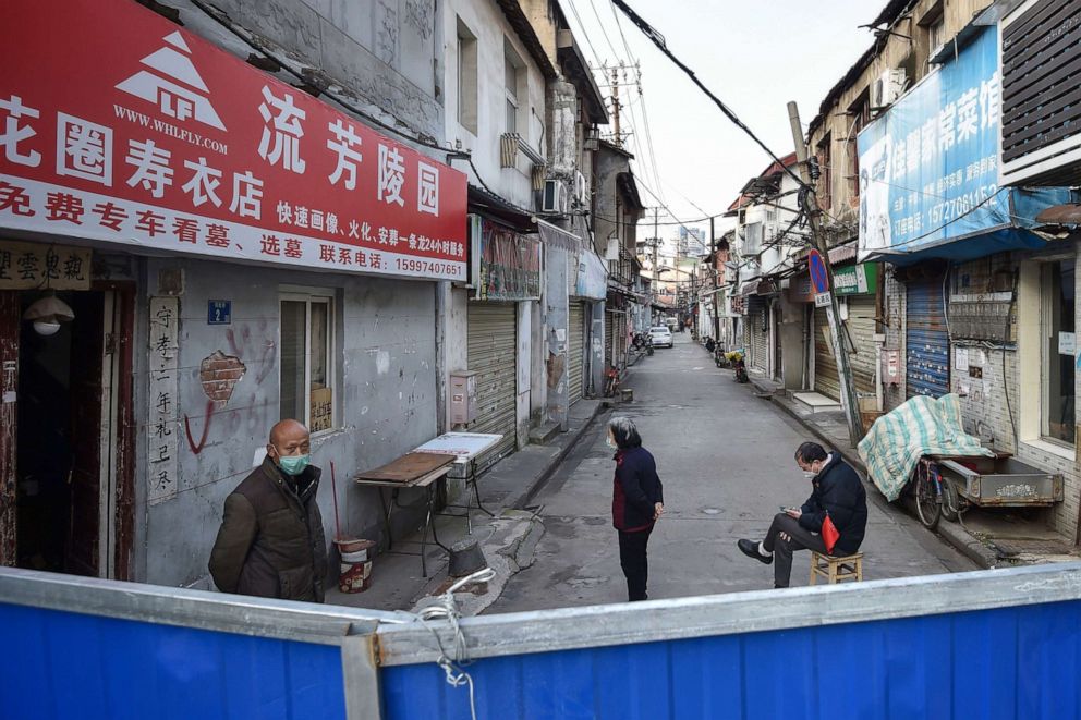 PHOTO: People stand on a street behind a barrier to stop others from entering, in Wuhan in China's central Hubei province, Feb. 23, 2020.