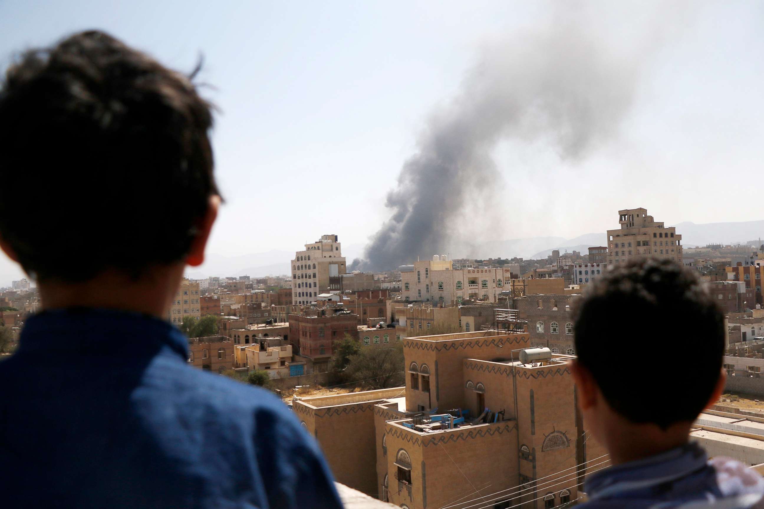 PHOTO: Children look on as smoke billows above the residential area following airstrikes of the Saudi-led coalition targeting Houthi-held military positions on March 07, 2021 in Sana'a, Yemen