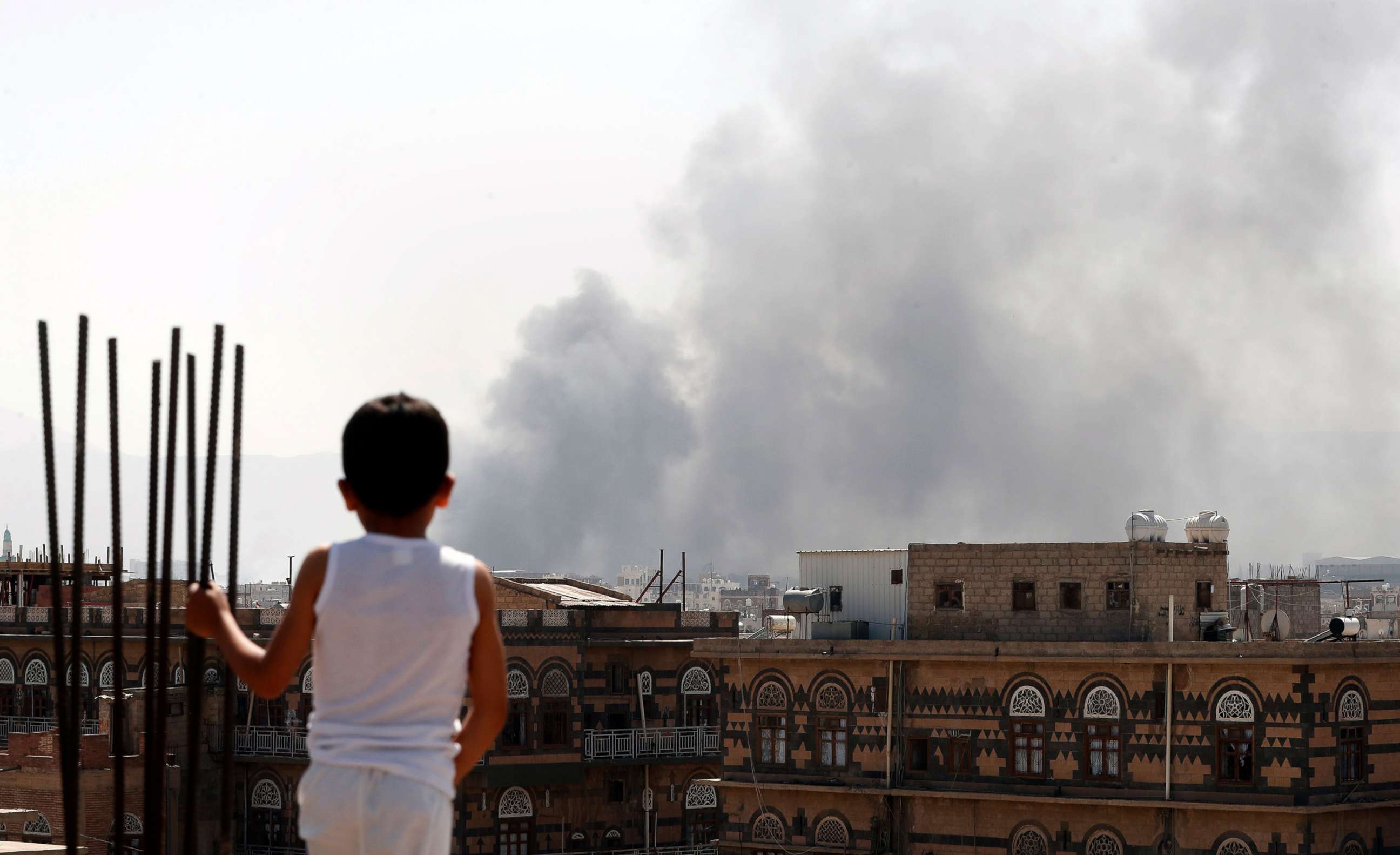PHOTO: A Yemeni boy looks at smoke billowing above a neighborhood following Saudi-led airstrikes targeting positions in Sana'a, Yemen, March 7, 2021.