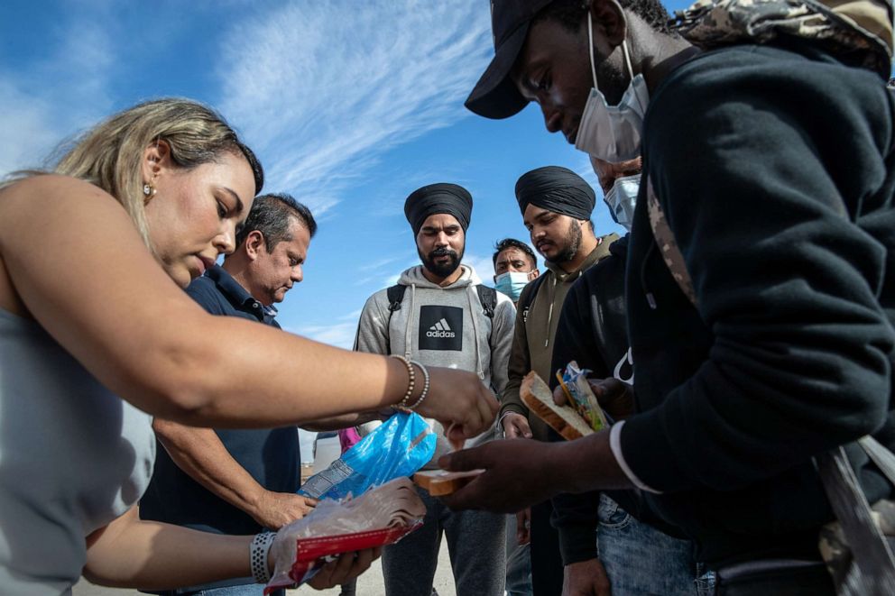 PHOTO: In this Dec. 9, 2021, file photo, immigrants from India and Haiti receive food from good Samaritans as they wait to be transported to a U.S. Border Patrol processing center in Yuma, Ariz.
