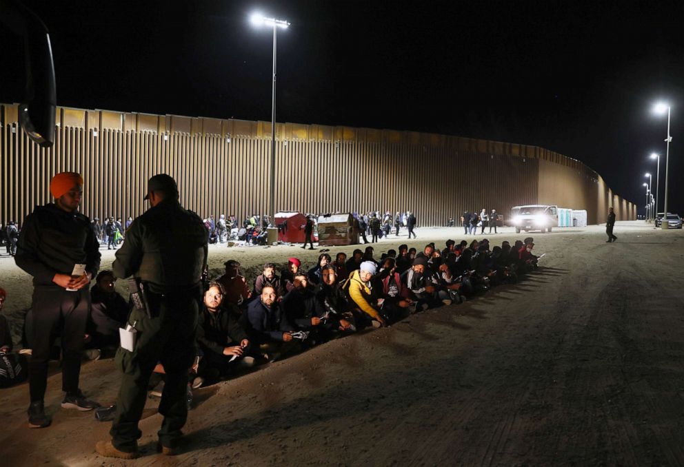 PHOTO: In this May 22, 2022, file photo, immigrants from India wait to board a U.S. Border Patrol bus to be taken for processing after crossing the border from Mexico, in Yuma, Ariz.