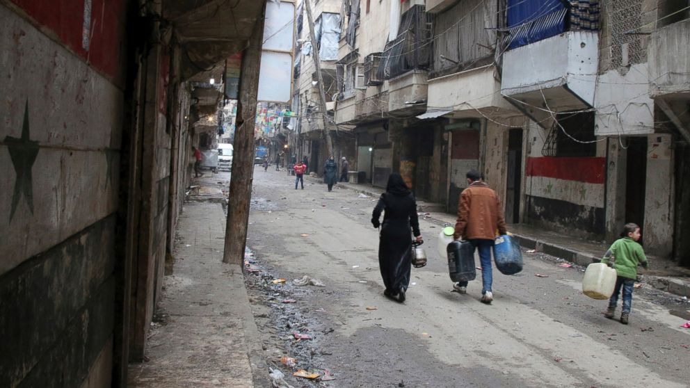 PHOTO: Civilians walk with containers for fuel and water in Aleppo, Syria.