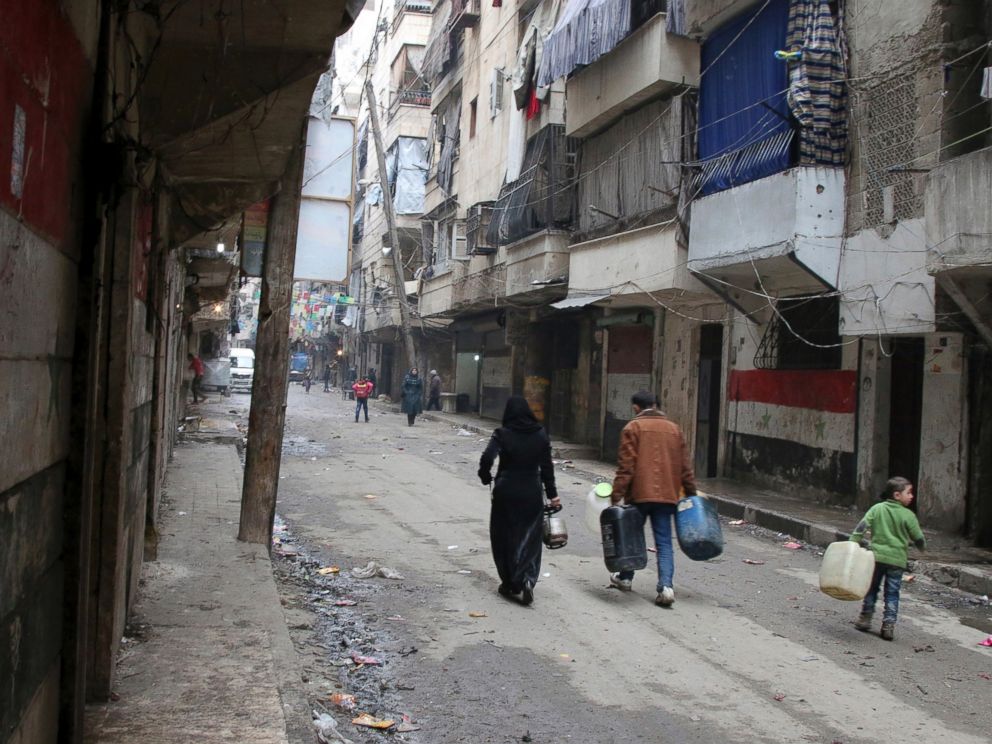 PHOTO: Civilians walk with containers for fuel and water in Aleppo, Syria.