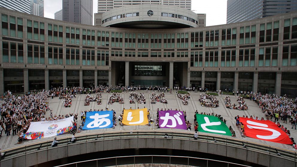 Tokyo citizens line up to form "Thank you" while others hold banners that read "Thank you" in Japanese to celebrate Tokyo winning the right to host the 2020 Summer Olympics in Tokyo, Sunday morning, Sept. 8, 2013. 