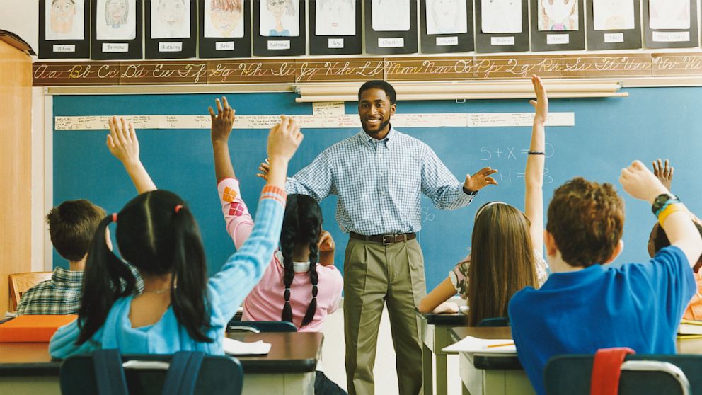 A teacher stands in front his students in a classroom.