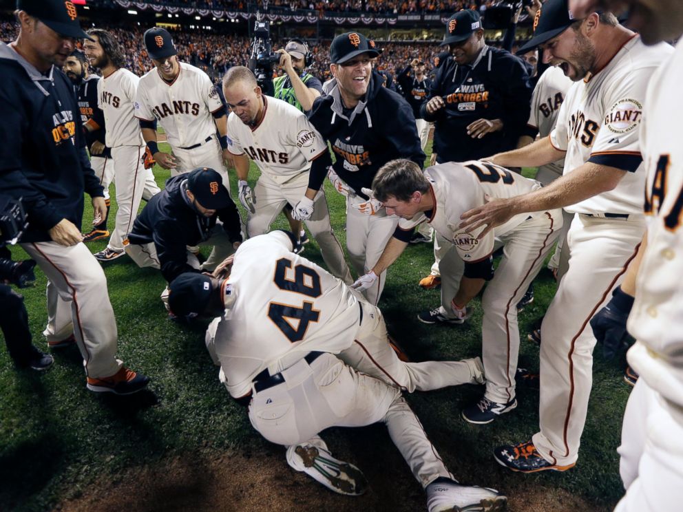 San Francisco Giants' Travis Ishikawa is swarmed by teammates after hitting a walk-off three-run home run during the ninth inning of Game 5 of the National League baseball championship series against the St. Louis Cardinals, Oct. 16, 2014.