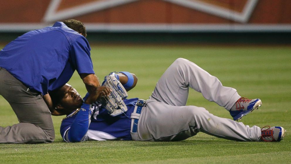Los Angeles Dodgers' Yasiel Puig is tended to by a trainer after he collided with teammate Howie Kendrick during the fifth inning of an exhibition baseball game against the Los Angeles Angels, April 2, 2015, in Anaheim, Calif.