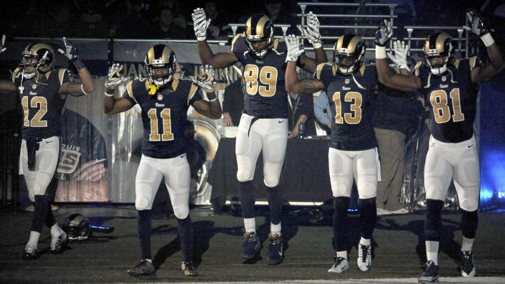 Members of the St. Louis Rams raise their arms in awareness of the events in Ferguson, Mo.,  as they walk onto the field during introductions before an NFL football game against the Oakland Raiders, Nov. 30, 2014, in St. Louis.