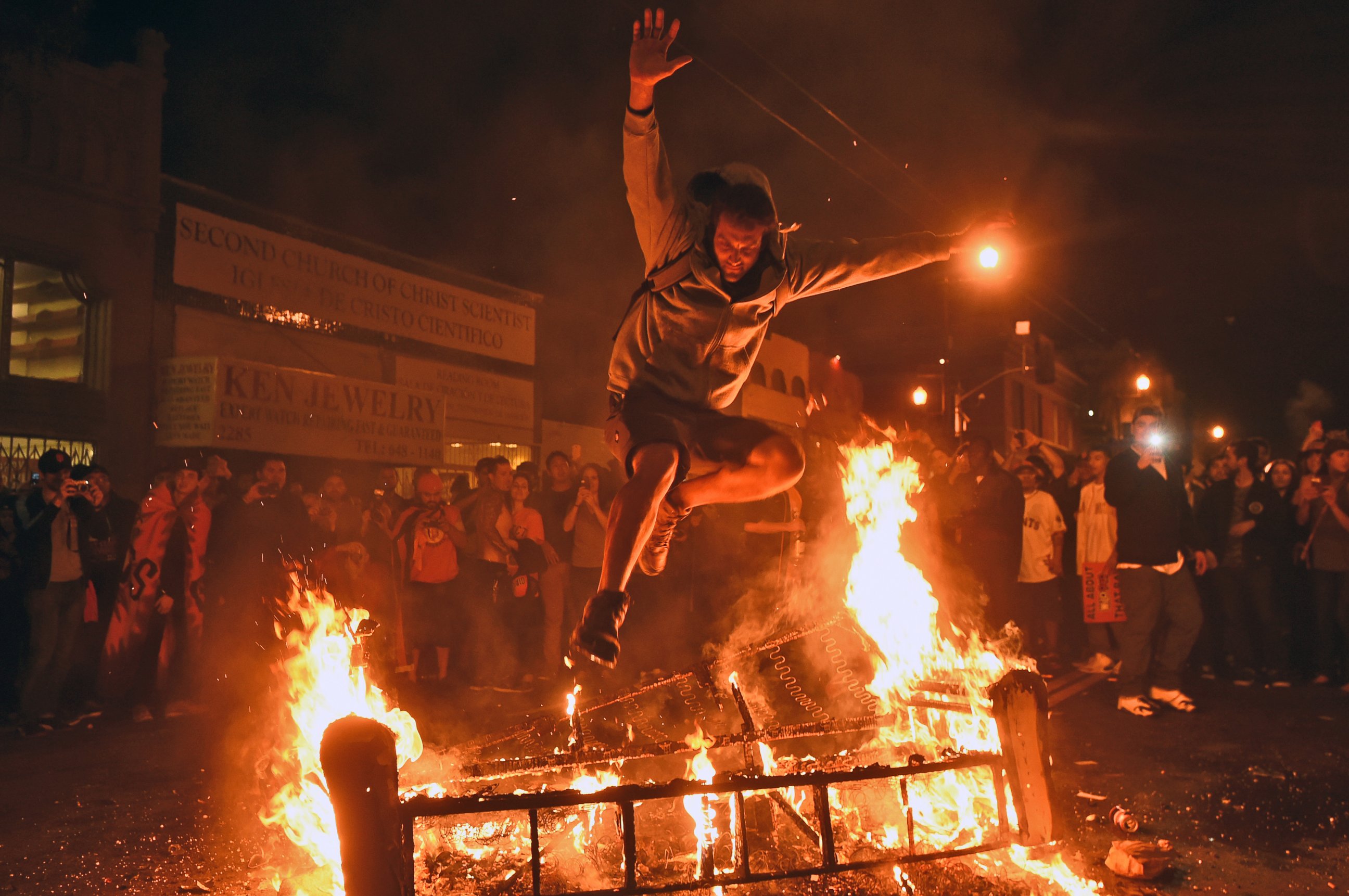 A man jumps over some debris that has been set on fire in the Mission district after the San Francisco Giants beat the Kansas City Royals to win the World Series on Wednesday, Oct. 29, 2014, in San Francisco.