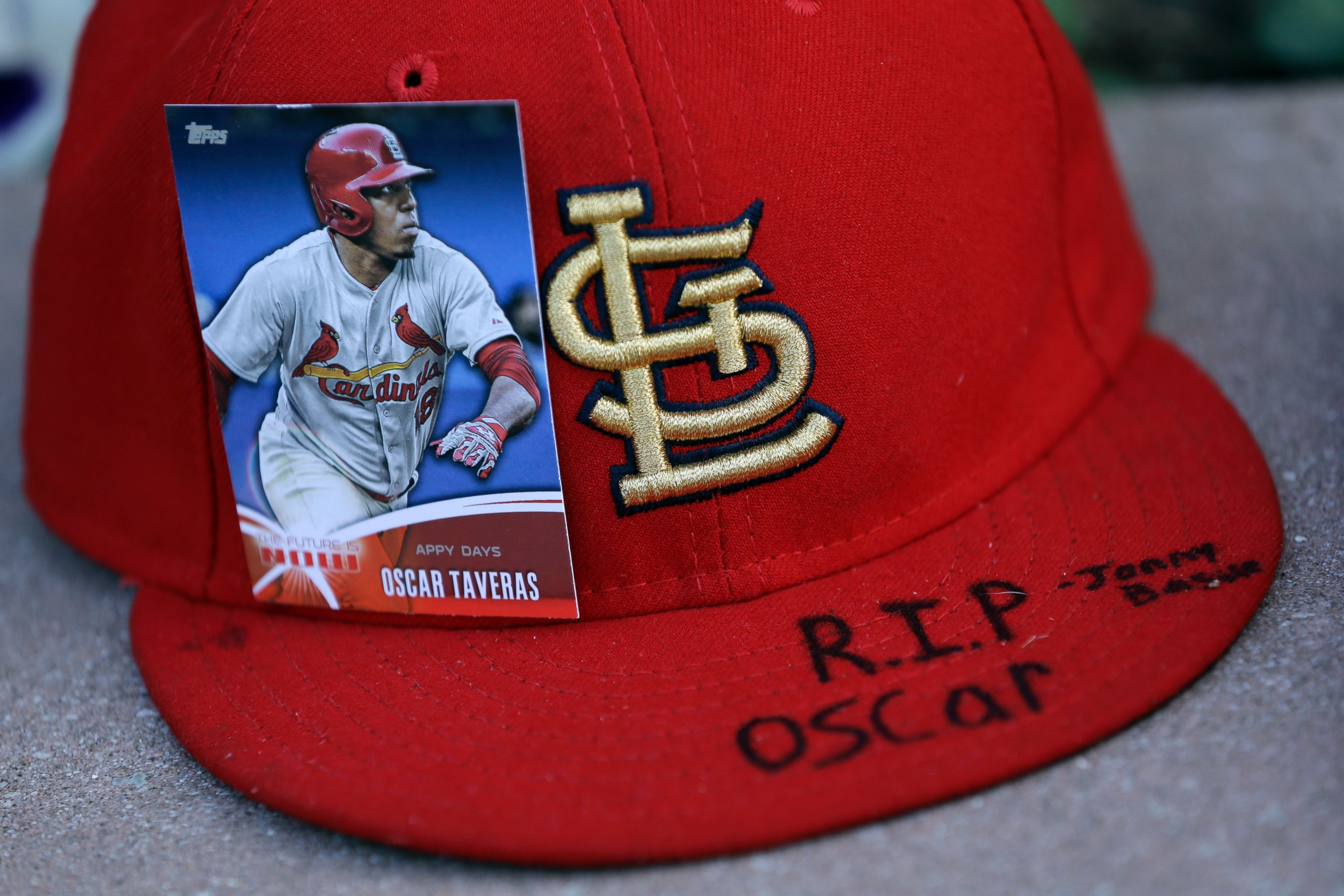 A baseball card showing St. Louis Cardinals' Oscar Taveras is attached to a hat as part of a makeshift memorial outside Busch Stadium, Oct. 27, 2014, in St. Louis.