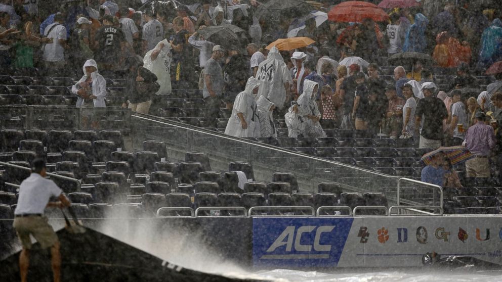 PHOTO: Fans scramble for cover as a rainstorm interrupts the fifth inning of a baseball game between the Texas Rangers and the New York Yankees at Yankee Stadium in New York, July 23, 2014.