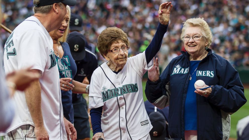 108-year-old Evelyn Jones, center, of Woodinville, Wash., waves to the crowd after throwing out the ceremonial first pitch on her birthday before a baseball game between the Seattle Mariners and the Los Angeles Angels, July 11, 2015, in Seattle. 
