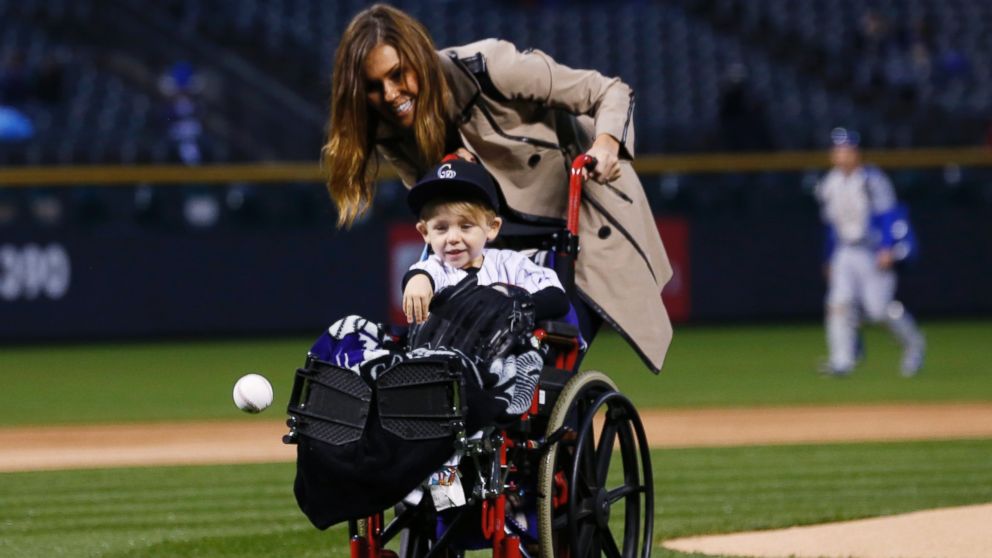 Two-year-old Jameson Axford throws out the ceremonial first pitch as his mother, Nicole, looks on before the Colorado Rockies host the Los Angeles Dodgers in a baseball game Friday, May 8, 2015, in Denver.