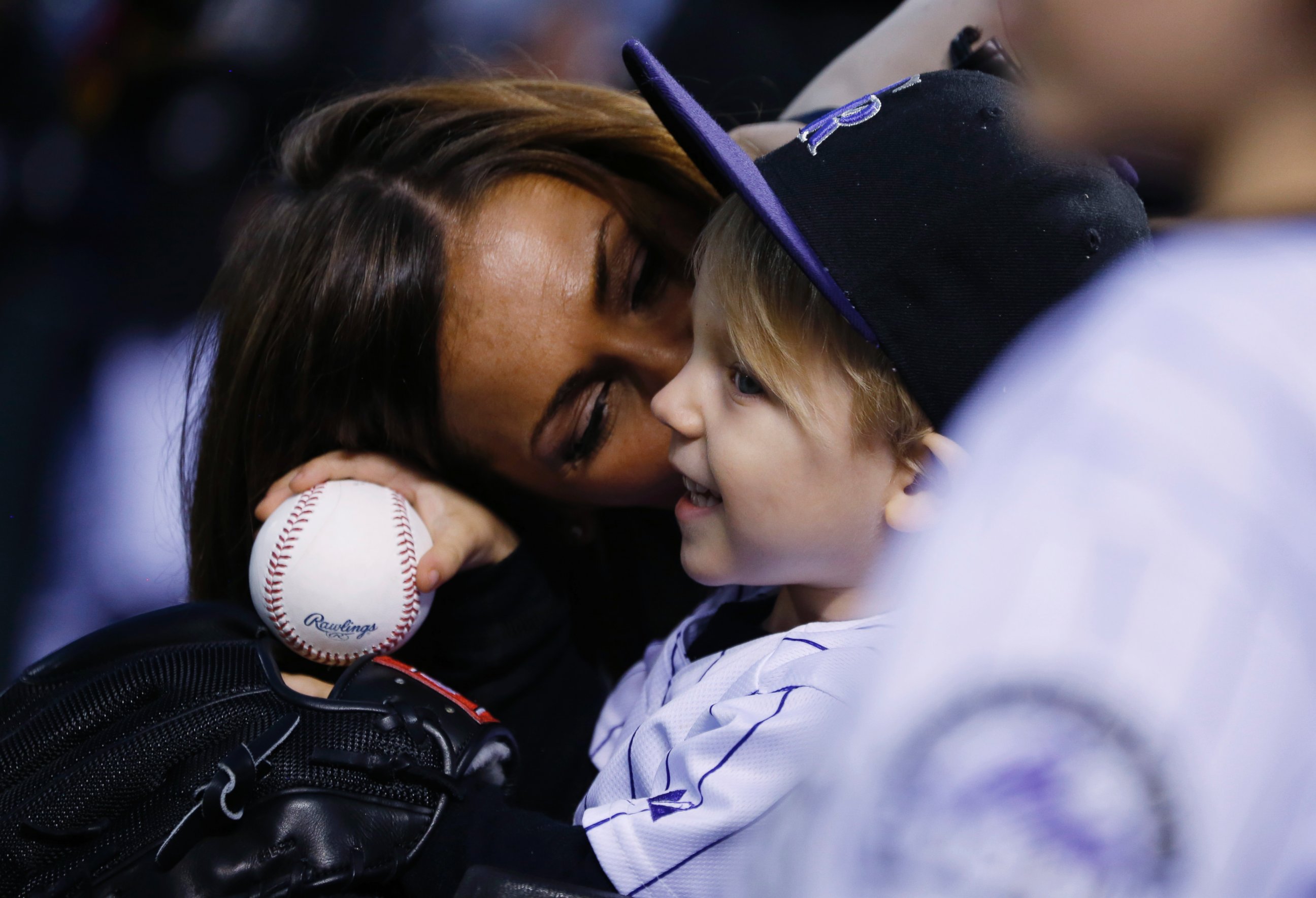 PHOTO: Nicole Axford, back, kisses her 2-year-old son, Jameson, as he waits to throw out the ceremonial first pitch before the Colorado Rockies host the Los Angeles Dodgers in a baseball game Friday, May 8, 2015, in Denver.