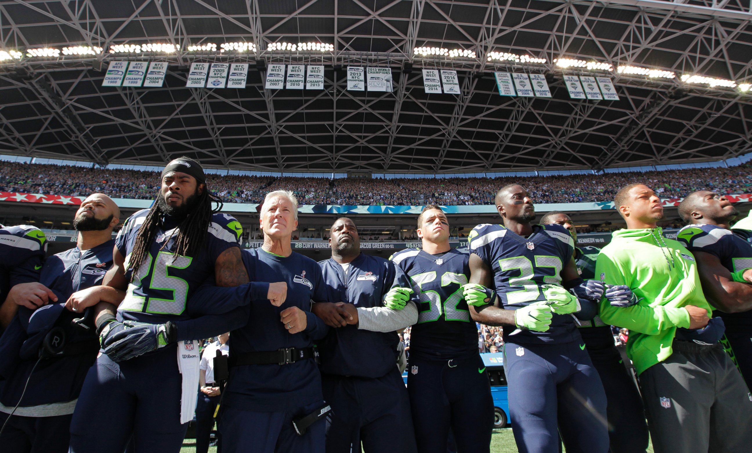 PHOTO: Seattle Seahawks players and coaches stand and link arms during the singing of the national anthem before an NFL football game against the Miami Dolphins, Sept. 11, 2016, in Seattle.