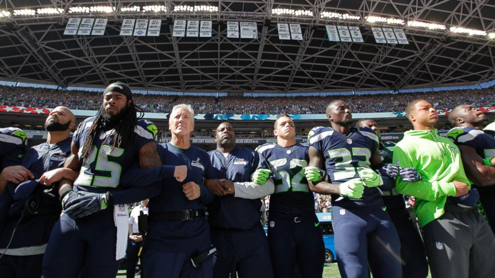 PHOTO: Seattle Seahawks players and coaches stand and link arms during the singing of the national anthem before an NFL football game against the Miami Dolphins, Sept. 11, 2016, in Seattle.
