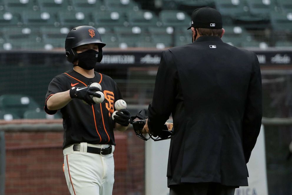 PHOTO: San Francisco Giants ball kid Austin Ginn, left, brings balls to umpire Brian Knight during the first inning of an exhibition baseball game between the Oakland Athletics and the Giants in San Francisco, Tuesday, July 21, 2020.
