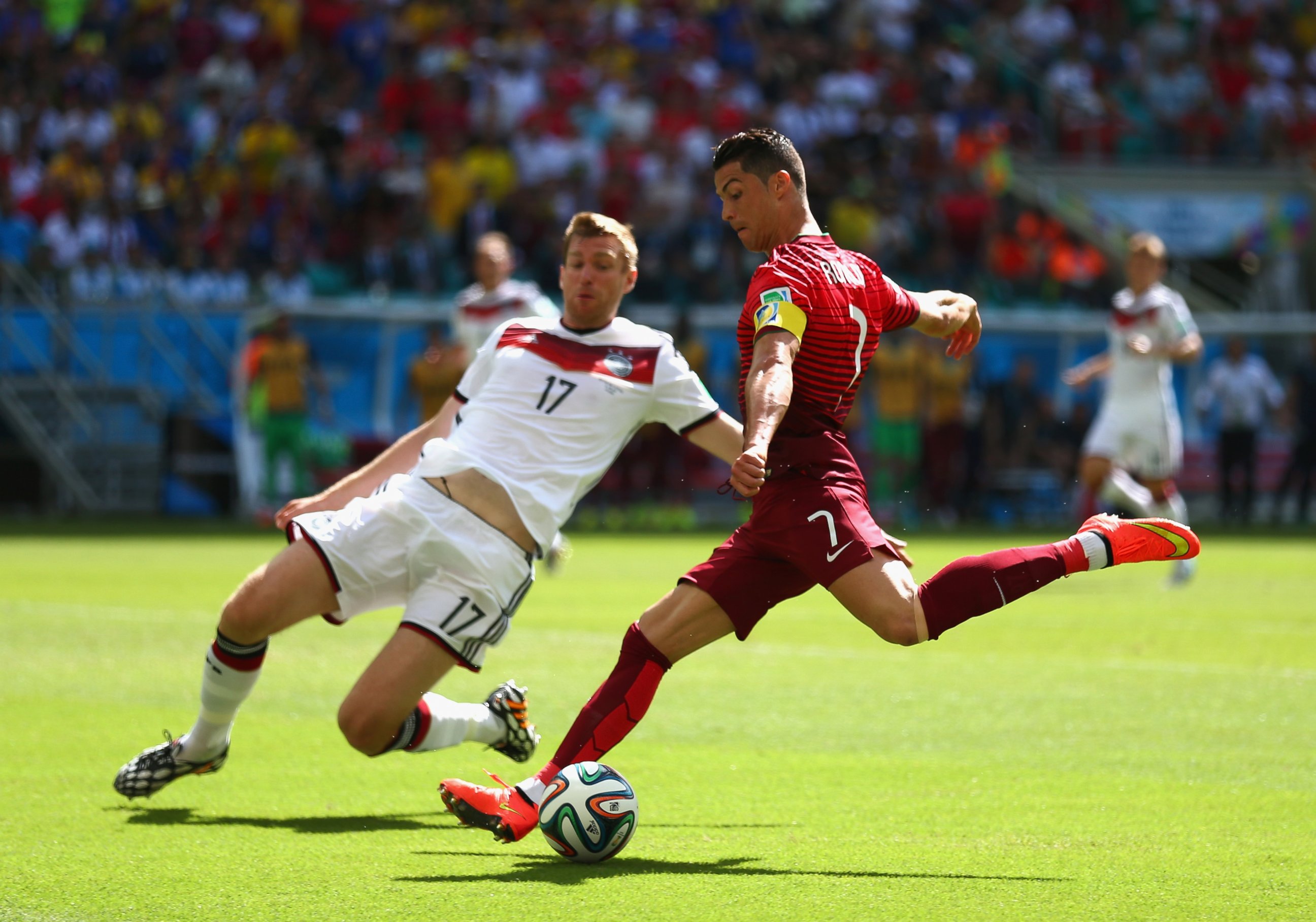 PHOTO: Cristiano Ronaldo of Portugal shoots against Per Mertesacker of Germany during the 2014 FIFA World Cup Brazil Group G match between Germany and Portugal at Arena Fonte Nova on June 16, 2014 in Salvador, Brazil. 