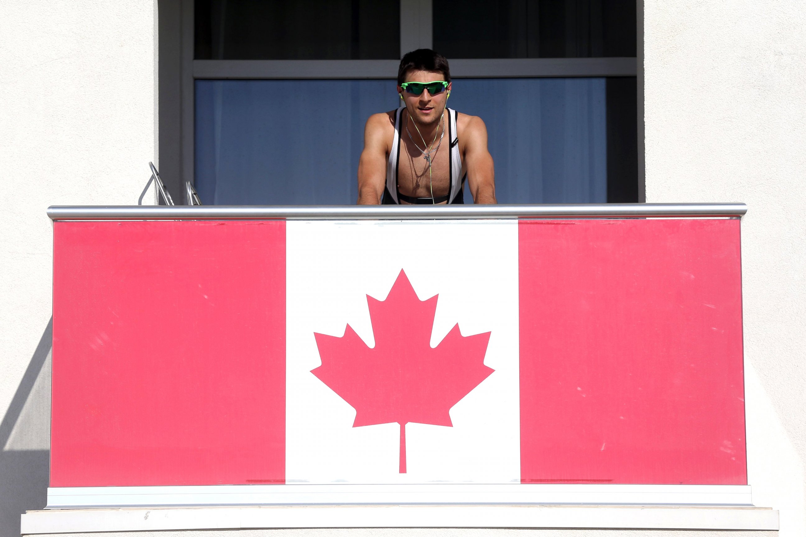 PHOTO: A member of the Canadian team takes advantage of warm weather to work out on his balcony in Olympic Village at the Winter Olympics in Sochi, Russia, Feb. 6, 2014.