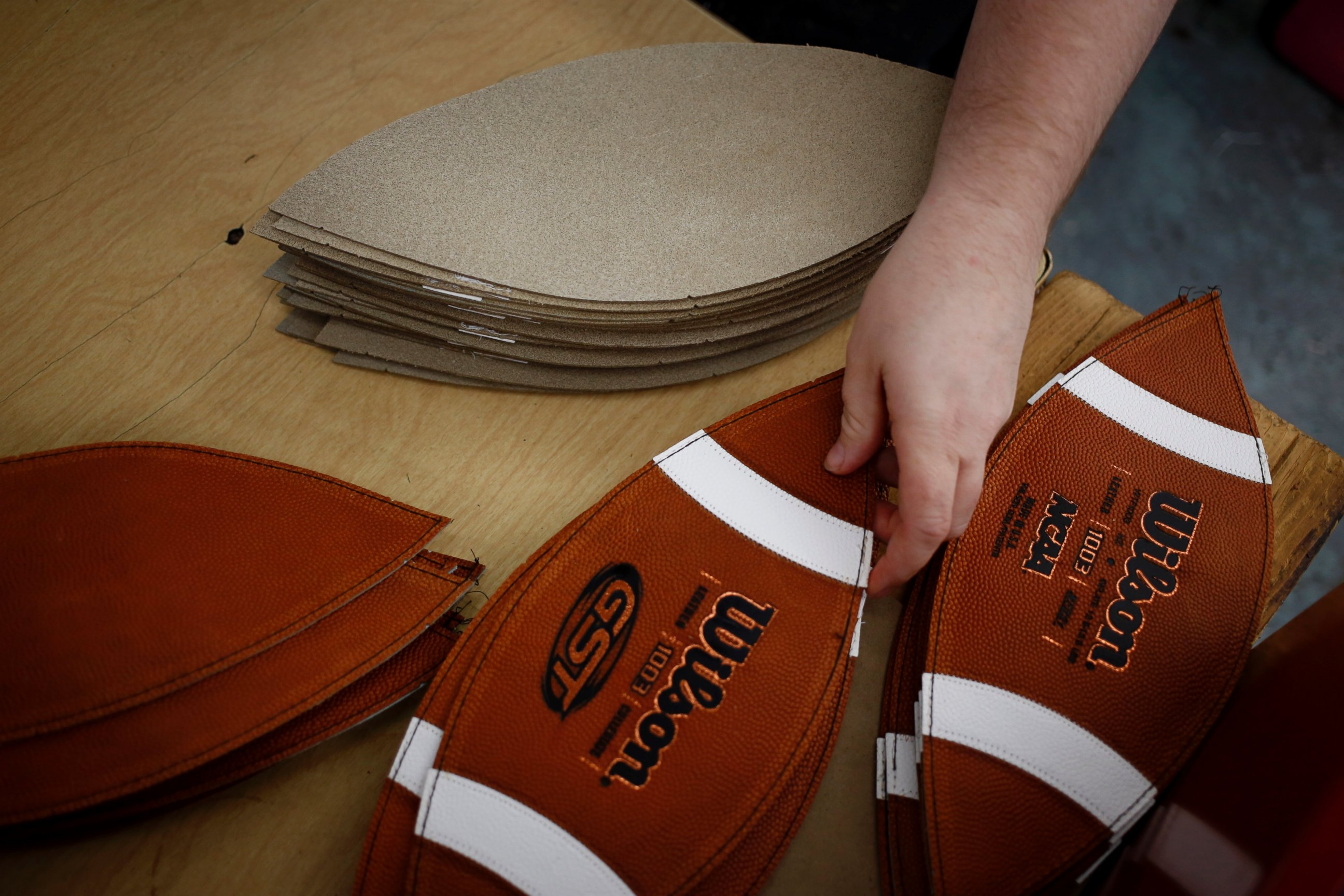 PHOTO: A worker reaches for a piece of leather to sew while manufacturing footballs at the Wilson Sporting Goods Co. factory in Ada, Ohio, Jan. 26, 2015. 