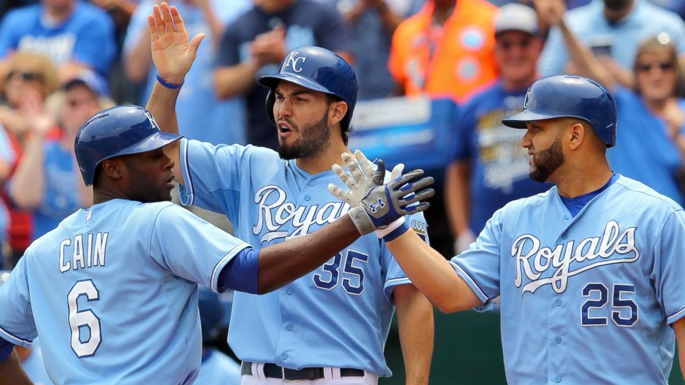 Lorenzo Cain #6 of the Kansas City Royals is congratulated at home plate by Eric Hosmer #35, and Kendrys Morales #25 after hitting a two-run homerun against the Tampa Bay Rays at Kauffman Stadium, July 9, 2015, in Kansas City, Missouri.