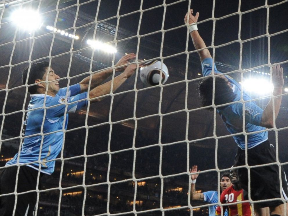 PHOTO: Uruguays striker Luis Suarez, left, stops the ball with his hand during the 2010 World Cup in Soweto, South Africa.