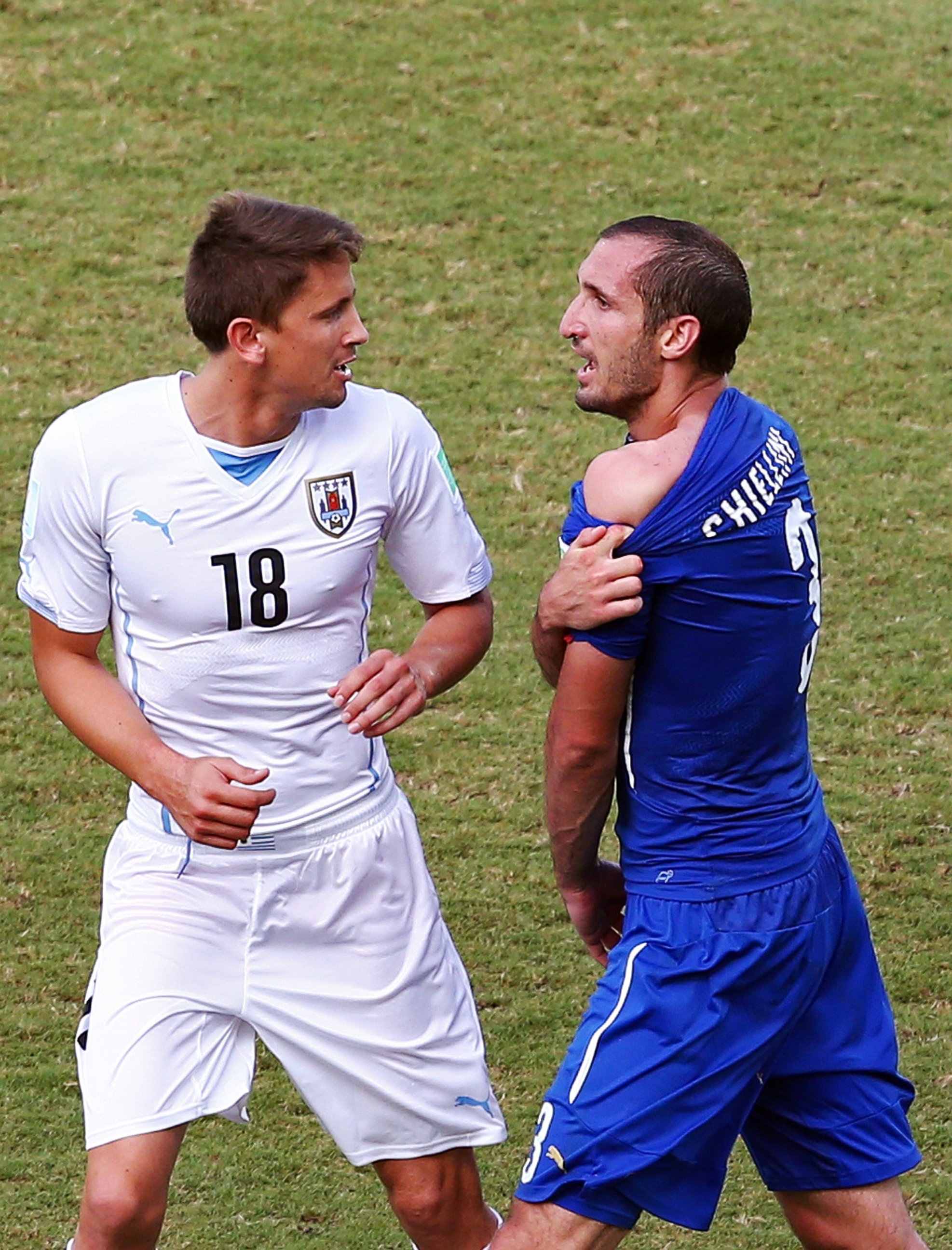 PHOTO: Giorgio Chiellini of Italy pulls down his shirt after a clash with Luis Suarez of Uruguay (not pictured) as Gaston Ramirez of Uruguay looks on during the match between Italy and Uruguay at Estadio das Dunas on June 24, 2014 in Natal, Brazil.  