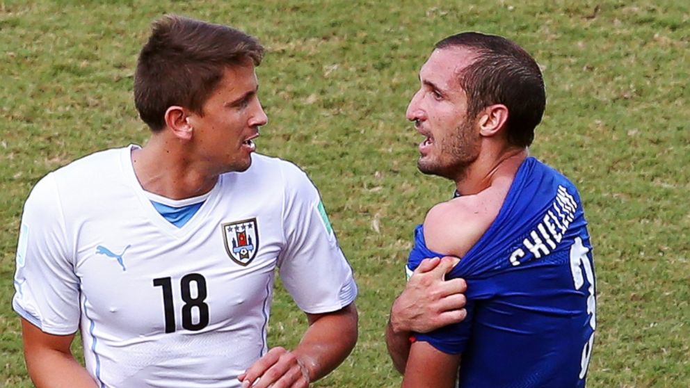 PHOTO: Giorgio Chiellini of Italy pulls down his shirt after a clash with Luis Suarez of Uruguay (not pictured) as Gaston Ramirez of Uruguay looks on during the match between Italy and Uruguay at Estadio das Dunas on June 24, 2014 in Natal, Brazil.  