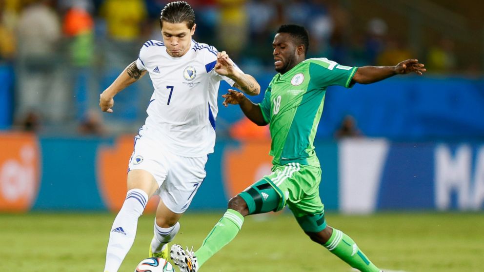 Muhamed Besic of Bosnia and Herzegovina is challenged by Michael Babatunde of Nigeria during the 2014 FIFA World Cup Group F match between Nigeria and Bosnia-Herzegovina at Arena Pantanal on June 21, 2014 in Cuiaba, Brazil.