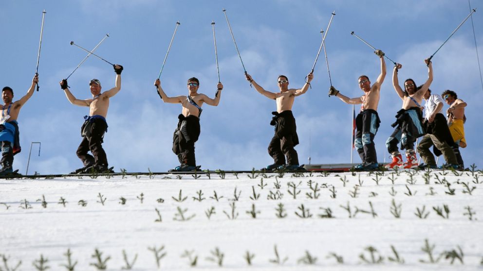 Course workers take off their shirts to enjoy the warm weather as they prepare the landing hill before the men's Nordic combined normal hill training jump at the RusSki Gorki Jump Center at the 2014 Sochi Winter Olympics. The snow was too warm and one training jump was cancelled due to slushy conditions.