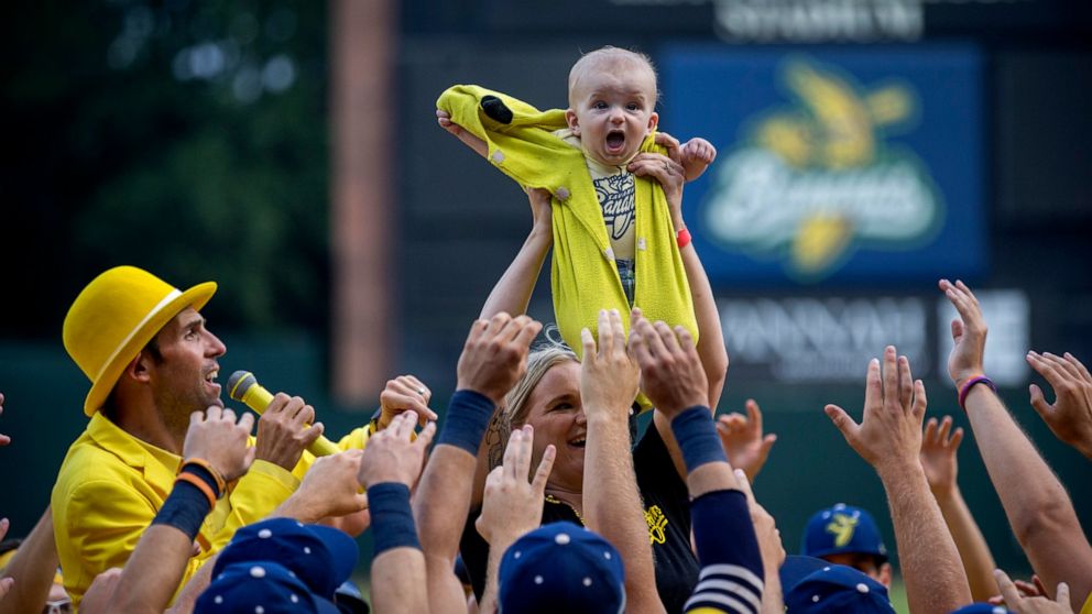 Molly Knutson holds her baby James Knutson high above the players as the Savannah Bananas present the Banana Baby to the crowd while playing the theme song from the movie "Lion King" over the public address system, Saturday, June 11, 2022, in Savanna