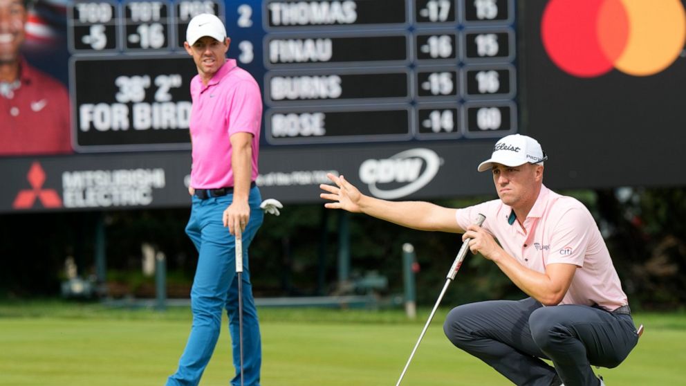 Justin Thomas, right, gestures for fans to stop moving as he and Rory McIlroy line up their putts on the 16th green during the final round of the Canadian Open golf tournament in Toronto, Sunday, June 12, 2022. (Frank Gunn/The Canadian Press via AP)
