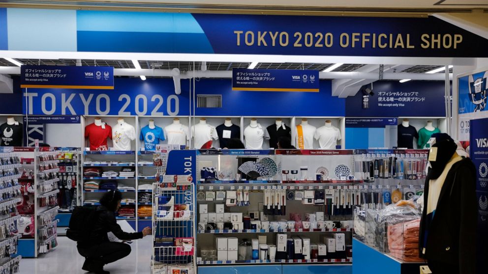 In this Jan. 8, 2020, file photo, a man looks at Olympic souvenirs at a Tokyo 2020 official shop in the Shinjuku district of Tokyo. Official Tokyo Olympic souvenir shops are drawing few customers these days. The pandemic and the fact the Olympics hav