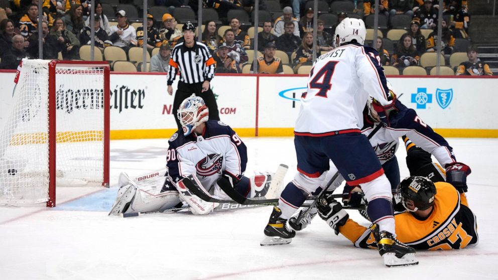 Pittsburgh Penguins' Sidney Crosby falls to the ice as he gets a shot past Columbus Blue Jackets goaltender Elvis Merzlikins for a goal during the second period of an NHL hockey game in Pittsburgh, Tuesday, Dec. 6, 2022. (AP Photo/Gene J. Puskar)